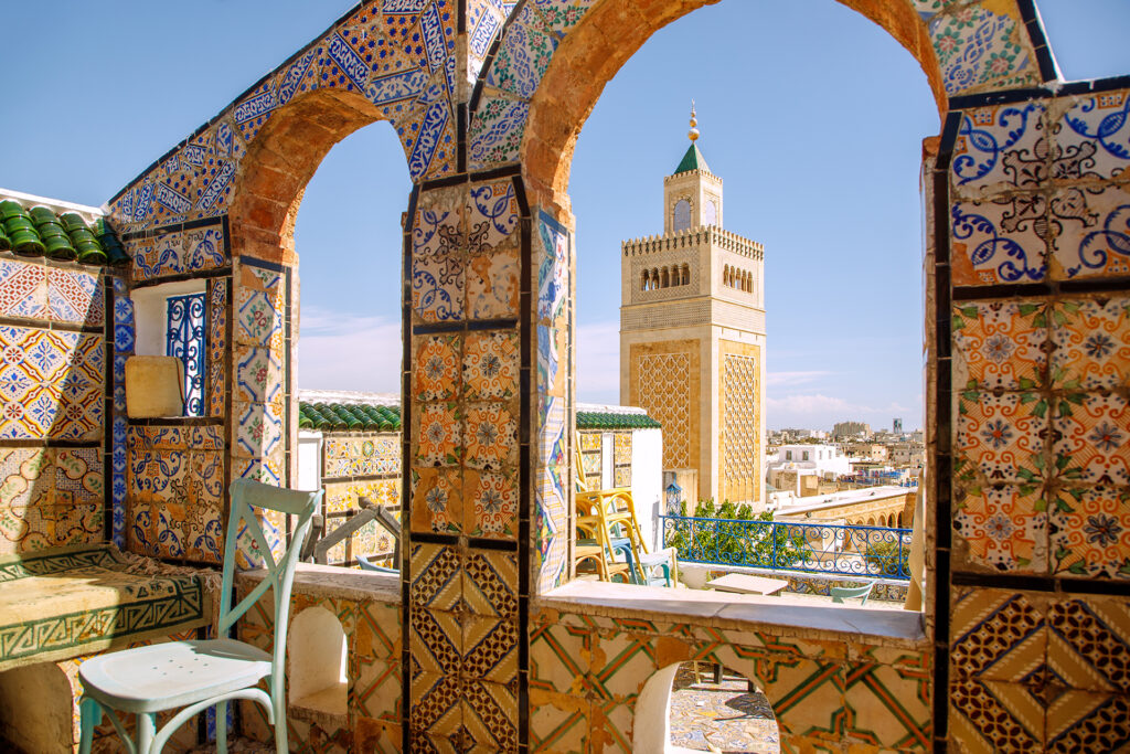 Dachterrasse des Café Panoramique mit bunten Fliesen und Blick auf die Große Moschee Djamaa ez-Zitouna in der Medina von Tunis, Tunesien.